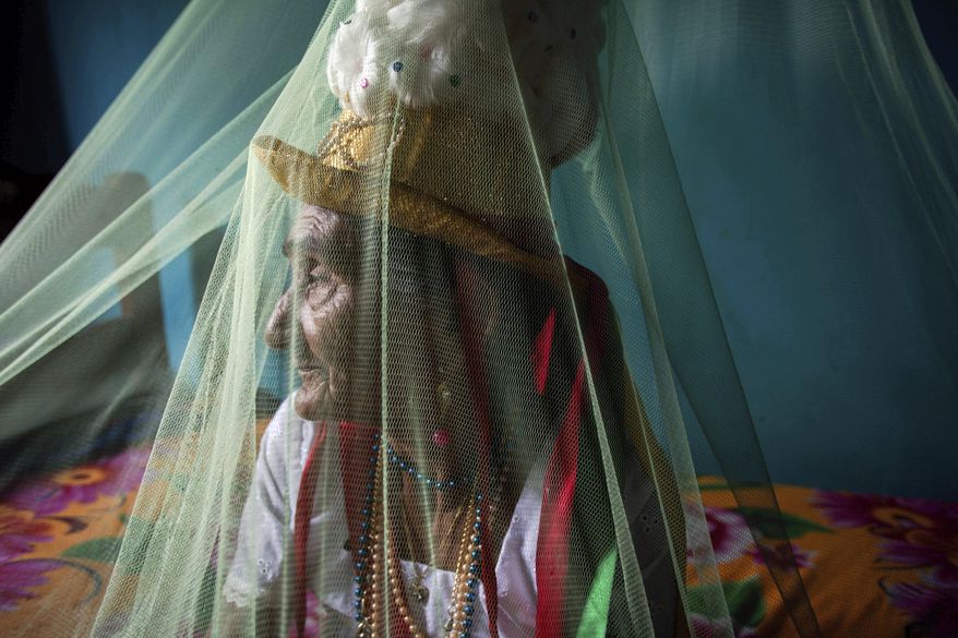 This Dec. 19, 2016 photo shows Clara Padilha Gomes preparing spiritually for the Marujada religious celebration, in honor of St. Benedict, at her home in the fishing town of Braganca, Brazil. Gomes, 77, said she participates to give thanks for her son. "As long as I'm alive, I will be devoted," she said. "A person has to have faith." (AP Photo/Eraldo Peres)
