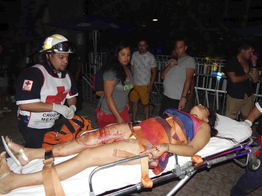 In this photo released by Por Esto de Quintana Roo, a first responder aids a woman wounded after a shooting at an electronic music festival in the Caribbean coast resort of Playa del Carmen, Mexico, early Monday, Jan. 16, 2017. The deadly shooting occurred in the early morning hours outside the Blue Parrot nightclub while it was hosting part of the BPM electronic music festival, according to police. (Por Esto de Quintana Roo, via AP)