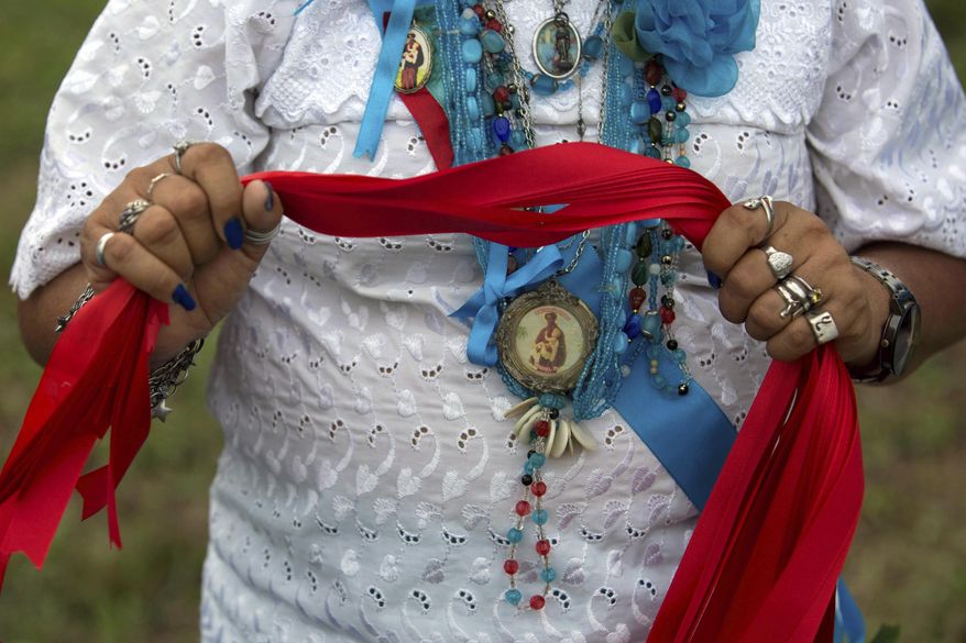 This Dec. 25, 2016 photo shows a woman holding red ribbons for the champion of the Cavalhada horse riding event during the Marujada religious celebration in honor of St. Benedict in the fishing town of Braganca, Brazil. Galloping horsemen compete to place a small stick through a small ring in the air. (AP Photo/Eraldo Peres)