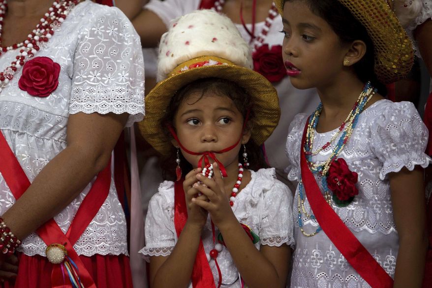 This Dec. 26, 2016 photo shows a girl attending Marujada religious celebrations in honor of St. Benedict in the fishing town of Braganca, Brazil. On this day of the days-long tradition, people dress in red, a color also seen in street decorations, as the city begins a day of partying. (AP Photo/Eraldo Peres)