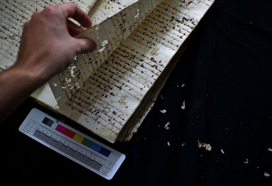 This Jan. 12, 2017 photo shows U.S. history professor David Lafevor handling a slave registry in the Espiritu Santo Church in Old Havana, Cuba. Slavery was outlawed in Cuba in 1819, but American slavers continued to use the island as a transshipment point for African slaves destined for U.S. slave markets in the south. (AP Photo/Ramon Espinosa)