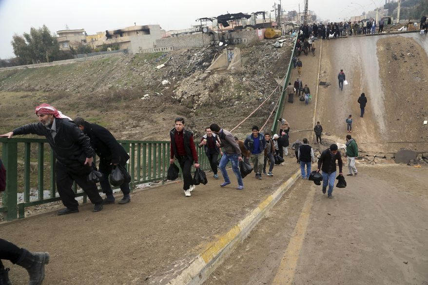 People cross a bridge destroyed by Islamic State militants in a neighborhood recently liberated from Islamic State on the eastern side of Mosul, Iraq, Sunday, Jan. 15, 2017. (AP Photo/ Khalid Mohammed)
