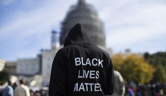 A man wears a hoodie that reads, &quot;Black Lives Matter&quot; as he stands on the lawn of the Capitol building on Capitol Hill in Washington during a rally to mark the 20th anniversary of the Million Man March, Oct. 10, 2015. (AP Photo/Evan Vucci) ** FILE **