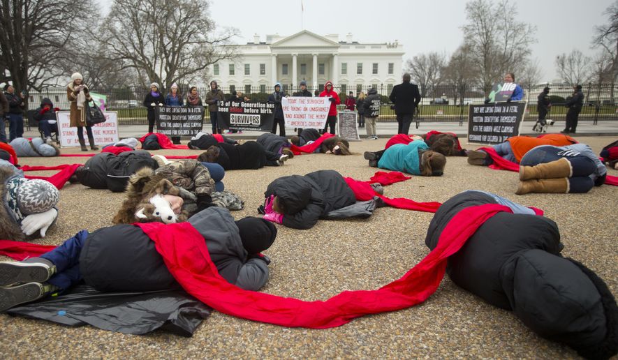 FILE - In a Wednesday, Jan. 21, 2015, file photo, anti-abortion rights activists are connected with a red piece of cloth as they stage a 'die-in' in front of the White House in Washington. Even as the 2016 election outcome intensifies America's abortion debate, a comprehensive new survey released Tuesday, Jan. 17, 2017 by the Guttmacher Institute finds the annual number of abortions in the U.S has dropped to well under 1 million, the lowest level since 1974. (AP Photo/Pablo Martinez Monsivais, File)