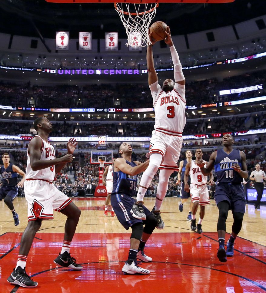 Chicago Bulls' Dwyane Wade (3) goes up for a dunk over Dallas Mavericks' Devin Harris and Dorian Finney-Smith (10) as teammate Bobby Portis watches during the first half of an NBA basketball game, Tuesday, Jan. 17, 2017, in Chicago. (AP Photo/Charles Rex Arbogast)