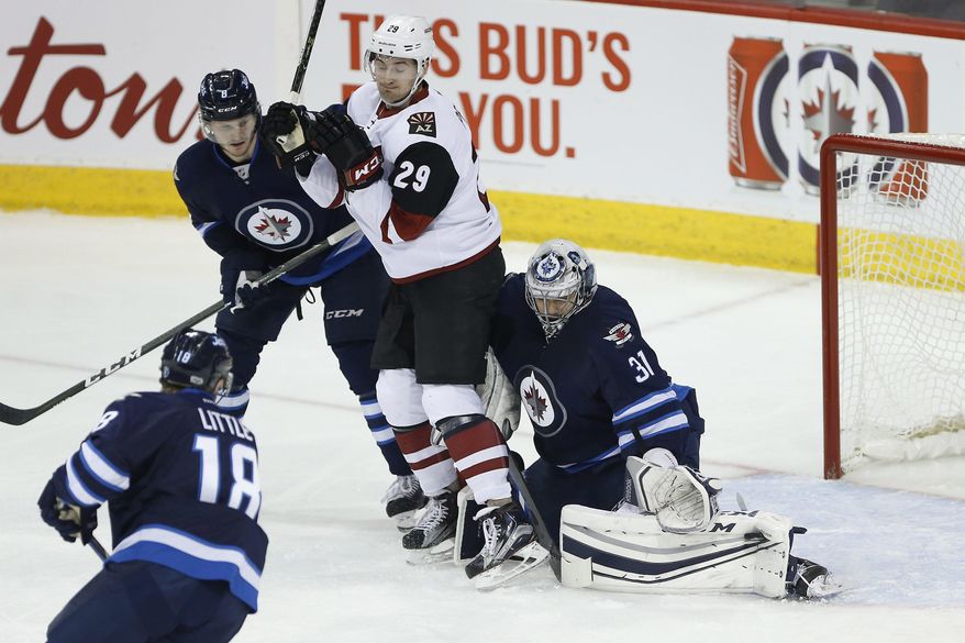 Winnipeg Jets goaltender Ondrej Pavelec (31) saves the shot as Jets' Jacob Trouba (8) and Arizona Coyotes' Brendan Perlini (29) jostle for position and Jets' Bryan Little (18) watches during the first period of an NHL hockey game Wednesday, Jan. 18, 2017, in Winnipeg, Manitoba. (John Woods/The Canadian Press via AP)