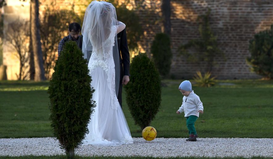 FILE - In this Nov. 9, 2013 file photo, a child plays with a ball next to a couple posing for a photographer in a park outside Bucharest, Romania. Newlywed couples took advantage of the unusual warm weather for the month of November, with temperatures reaching 20 degrees Celsius (68 degrees Fahrenheit), for outdoor photo sessions. Kiss goodbye some of those postcard-perfect, ideal-for-outdoor-wedding days. A new study said global warming is going to steal some of those exceedingly pleasant weather days from our future. On average, Earth will have four fewer days of mild and mostly dry weather by 2035 and ten fewer of them by the end of the century, according to a first-of-its-kind projection of nice weather. (AP Photo/Vadim Ghirda, File)