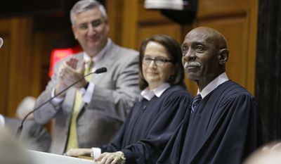 Indiana Supreme Court Justice Robert Rucker, right, is introduced after Chief Justice Loretta H. Rush, center, announced his impending retirement as she delivered her State of the Judiciary address to a joint session of the legislature at the Statehouse in Indianapolis, Wednesday, Jan. 18, 2017. Gov. Eric Holcomb is at the left. Rucker will retire this year after 18 years on the court.  (AP Photo/Michael Conroy)