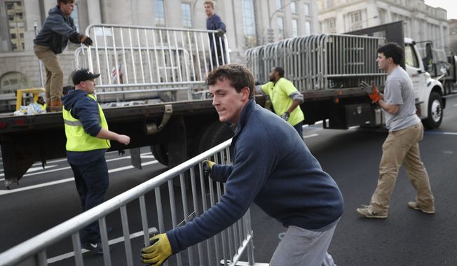 Workers unload barricades before placing them along Pennsylvania Avenue in Washington as security tightens ahead of the presidential inauguration. (Associated Press)