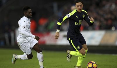 Arsenal&#39;s Mesut Ozil, right, Swansea City&#39;s Nathan Dyer battle for the ball during the English Premier League soccer match between Swansea City and Arsenal at the Liberty Stadium, Swansea, Wales, Saturday, Jan. 14, 2017.(Nick Potts/PA via AP)