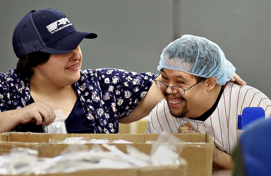 ADVANCE FOR WEEKEND EDITIONS - In this Friday, Jan. 6, 2017, photo, Stephanie Gravuer and Luis Reyes share a laugh while working at Associated Production Services Inc. in Lower Southampton Township, Pa. The assembly and packaging company provides vocational training to adults with disabilities and employs nearly 600 workers at sites throughout Greater Philadelphia. (Kim Weimer/Bucks County Courier Times via AP)