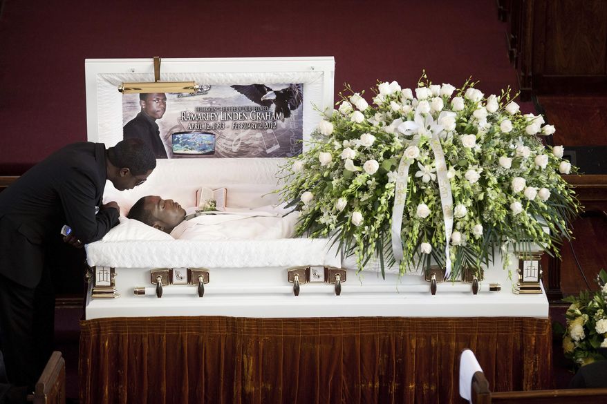 FILE - In this Feb. 18, 2012, file photo, Franclot Graham leans over his son, Ramarley Graham, in his casket before funeral services in the Bronx borough of New York. Officer Richard Haste initially faced a criminal manslaughter charge in the 2012 death of 18-year-old, Graham, but the case was ultimately dismissed. Haste was expected to offer his first public account of the slaying at his department disciplinary trial on Friday, Jan 20, 2017. (AP Photo/John Minchillo, File)