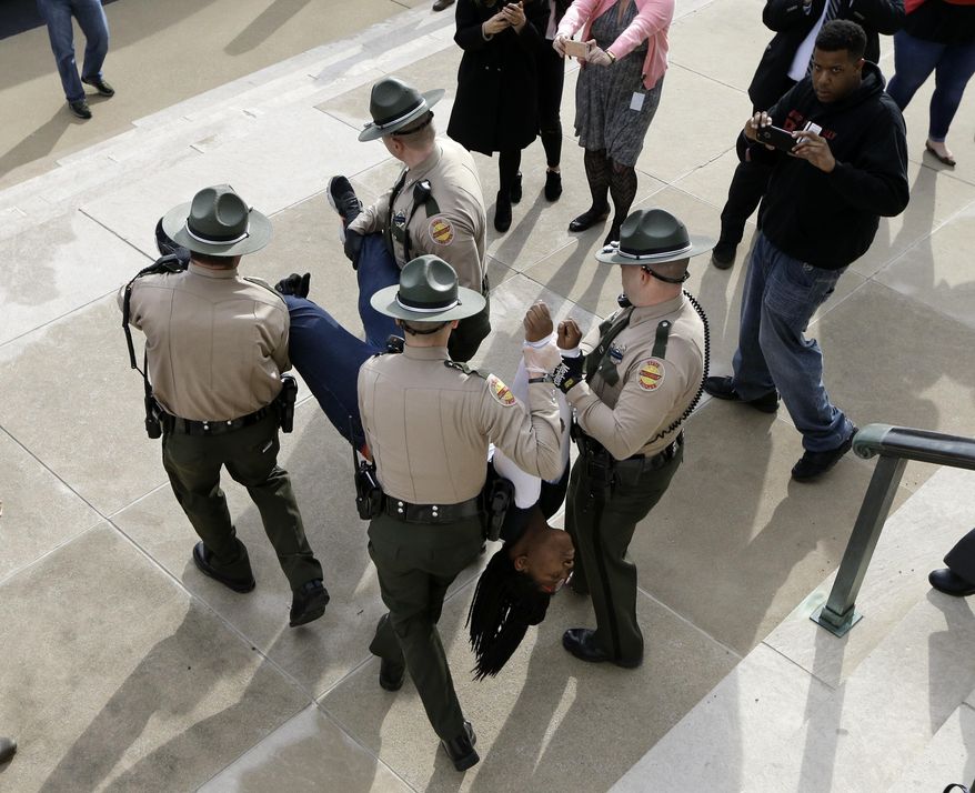 A protester is carried away from the Capitol, Friday, Jan. 20, 2017, in Nashville, Tenn. Protesters chained themselves to one another and to the Capitol building and emergency workers had to cut them free. The protest centered on the inauguration of President Donald Trump but included other social issues. (AP Photo/Mark Humphrey)
