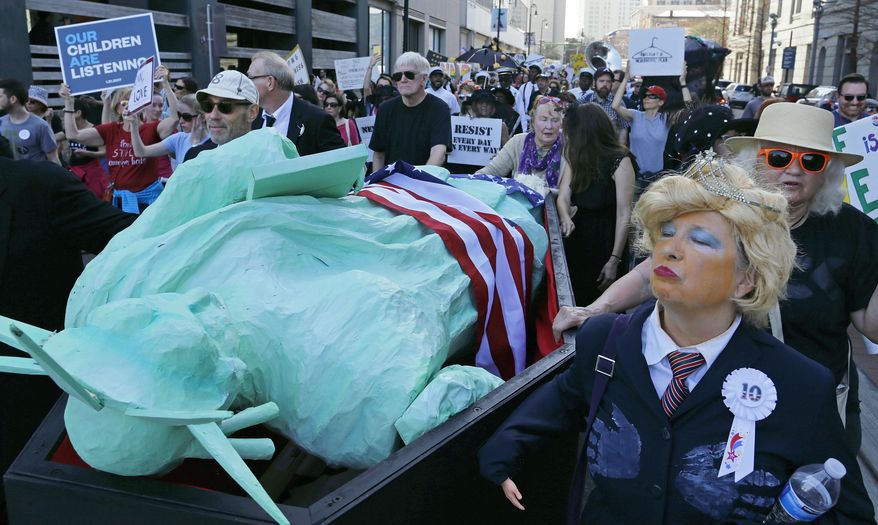 Protesters, one dressed as President Donald Trump, carry a coffin containing The Statue of Liberty down the streets of New Orleans in protest against Trump's inauguration in Friday, Jan. 20, 2017. (AP Photo/Max Becherer)