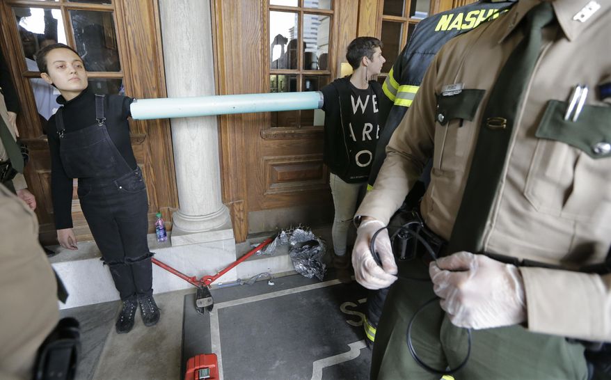 Protesters stand connected to one another with chain and plastic pipe at the state Capitol building Friday, Jan. 20, 2017, in Nashville, Tenn. The protest centered on the inauguration of President Donald Trump but included other social issues. (AP Photo/Mark Humphrey)