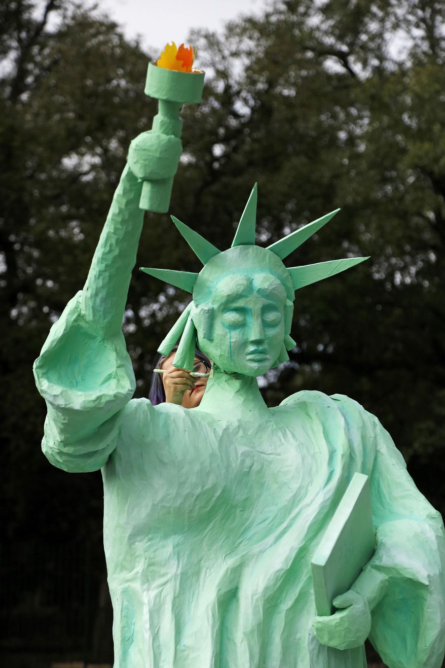 Artist Chandra Leming paints a Statue of Liberty sculpture she created for a protest against the inauguration of Donald Trump at Louis Armstrong Park in New Orleans, Friday, Jan. 20, 2017. Donald J. Trump will be sworn in as the 45th President of the United States Friday. (AP Photo/Max Becherer)