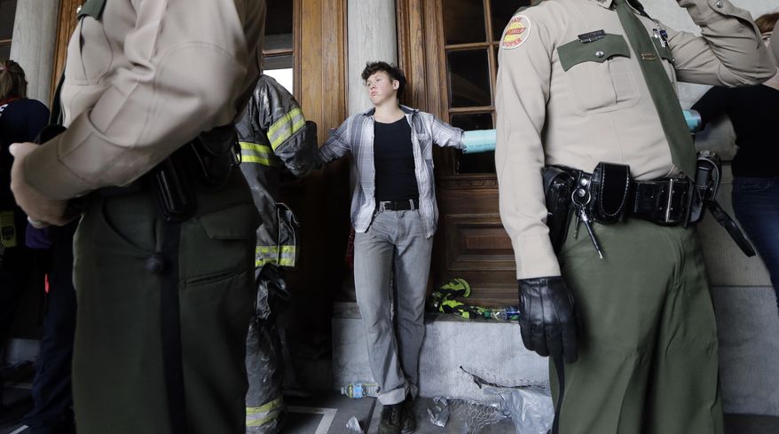 A protester stands chained to other protesters as a firefighter works to free him at the state Capitol building Friday, Jan. 20, 2017, in Nashville, Tenn. The protest centered on the inauguration of President Donald Trump but included other social issues. (AP Photo/Mark Humphrey)