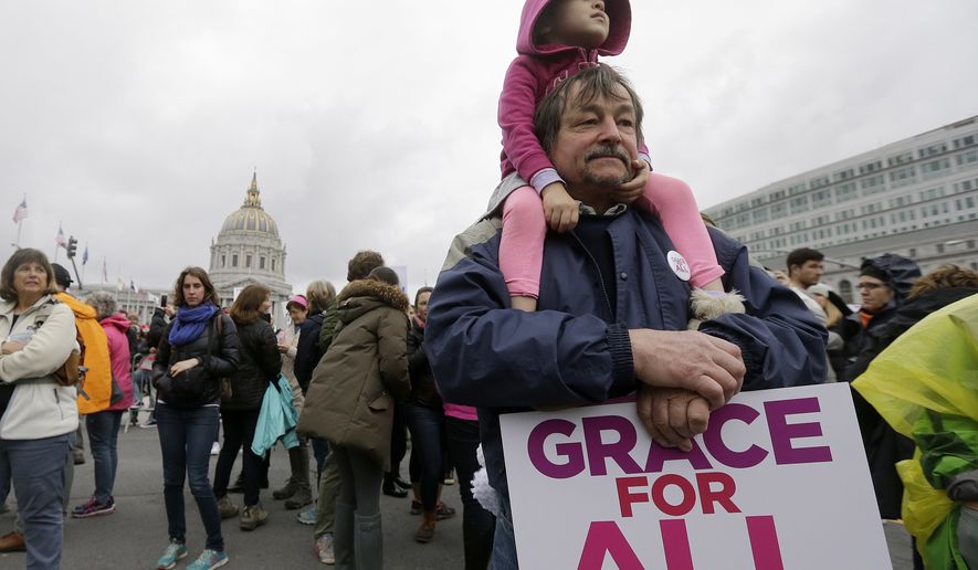 Michael Clark holds his daughter a rally before a women's march during the first full day of Donald Trump's presidency in San Francisco, Saturday, Jan. 21, 2017. (AP Photo/Jeff Chiu)