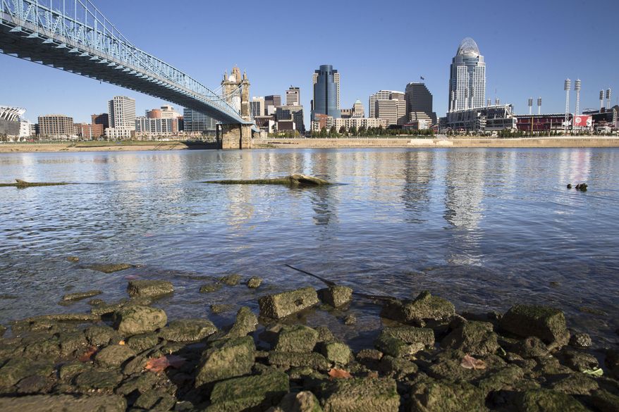 FILE – In this Oct. 16, 2015, file photo, algae coats rocks in view of Cincinnati's skyline on the banks of the Ohio River in Newport, Ky. As of early 2017, about 12,000 farmers and fertilizer applicators have completed Ohio's three-hour training program that soon will be required to use commercial fertilizer. The first-of-its-kind requirement, approved by Ohio lawmakers in 2014, is one step the state has taken to reduce farm runoff that feeds toxic algae in lakes and rivers. (AP Photo/John Minchillo, File)