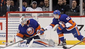New York Islanders goalie Jean-Francois Berube (30) blocks a shot by the Los Angeles Kings as New York Islanders defenseman Adam Pelech (50) reaches for the rebound during the second period of an NHL hockey game, Saturday, Jan. 21, 2017, in New York. (AP Photo/Julie Jacobson)