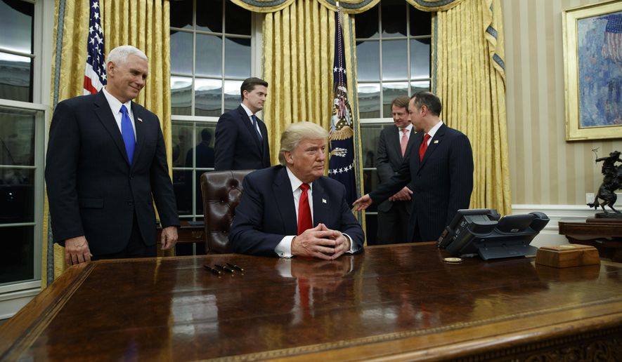 Vice President Mike Pence, left, watches as President Donald Trump prepares to sign his first executive order, Friday, Jan. 20, 2017, in the Oval Office of the White House in Washington. (AP Photo/Evan Vucci)