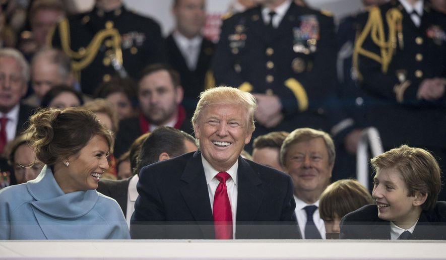 President Donald Trump shares a laugh with first lady Melania Trump and son Barron Trump as they sit in the reviewing stand during Trump's inaugural parade on Pennsylvania Ave. outside the White House in Washington, Friday, Jan. 20, 2017. (AP Photo/Andrew Harnik)
