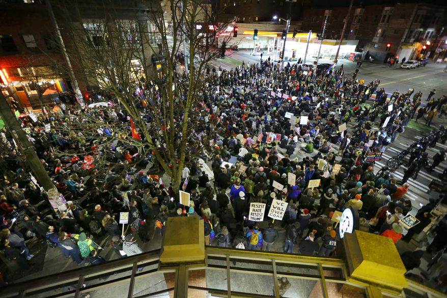 Hundreds of protesters sit down in the street at the intersection of Pike Street and Broadway during a protest against President Donald Trump, Friday, Jan. 20, 2017, in Seattle. (AP Photo/Ted S. Warren)