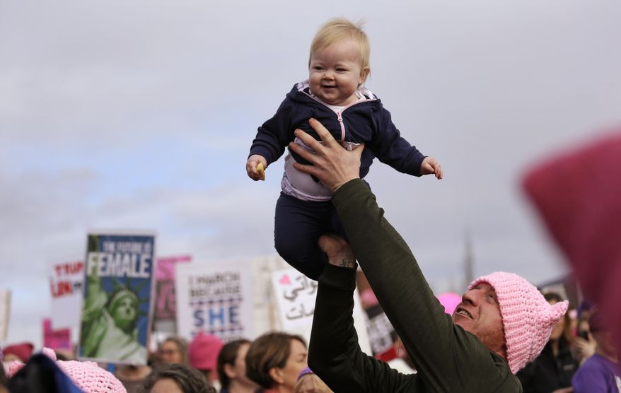 A man lifts a baby above the crowd before a women's march Saturday, Jan. 21, 2017, in Seattle. Women across the Pacific Northwest marched in solidarity with the Women's March on Washington and to send a message in support of women's rights and other causes. (AP Photo/Elaine Thompson)