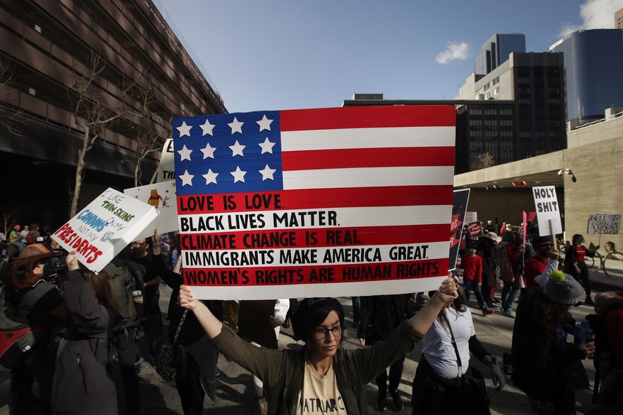 Protesters carry signs as they march along the street at the Women's Protest against President Donald Trump Saturday, Jan. 21, 2017, in Los Angeles. The march was held in in conjunction with with similar events taking place around the nation following the inauguration of Trump. (AP Photo/Jae C. Hong)