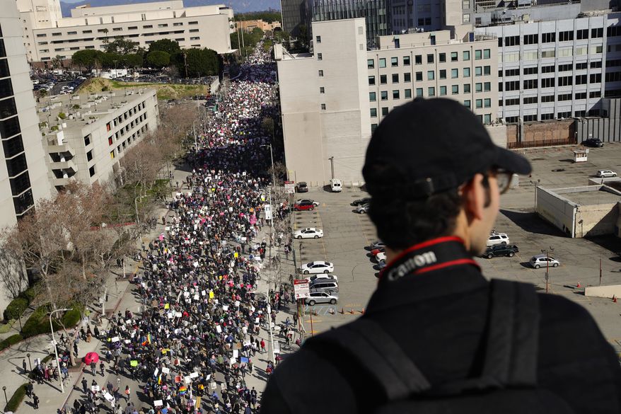 Derek Avila stands on the rooftop of a building as thousands of protesters fill the streets of downtown Los Angeles to protest against President Donald Trump, Saturday, Jan. 21, 2017. (AP Photo/Jae C. Hong)