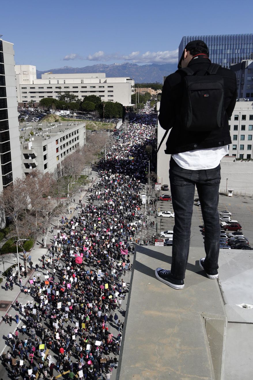Derek Avila stands on the rooftop of a building as thousands of protesters fill the streets of downtown Los Angeles to protest against President Donald Trump, Saturday, Jan. 21, 2017. (AP Photo/Jae C. Hong)