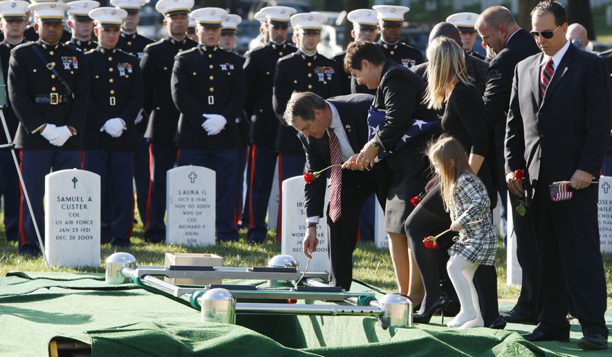 The family of Marine 1st Lt. Travis L. Manion drops roses into his gravesite during the reinternment ceremony for Manion, of Doylestown, Penn., at Arlington National Cemetery, in Arlington, Va. on Friday, Oct. 1, 2010. From center are Manion&#39;s father retired Marine Col. Thomas Manion, mother Janet Manion, sister Ryan Manion with her daughter Maggie Manion-Borek, 4, and brother-in-law David Borek. Manion was buried in Pennsylvania after being killed in Iraq in 2007, he is being reinterned at Arlington so that he can be buried next to his best friend, Marine Lt. Brendan Looney, who was killed in Afghanistan and will be buried on Monday. (AP Photo/Jacquelyn Martin)