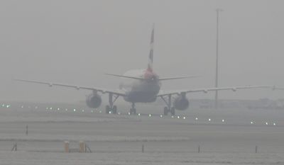 A British Airways plane is seen through dense fog on the tarmac at Heathrow Airport, London, Monday, Jan. 23, 2017. Thick fog has caused numerous flight delays and cancellations at London Heathrow and other area airports. The Met Office forecasting service said visibility at Heathrow had been reduced to roughly 100 meters (yards), leading to an overall slowdown in operations. (Steve Parsons/PA via AP)
