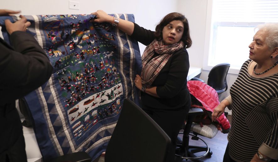 In a Wednesday, Jan. 18, 2017 photo, Neha Gill, center, executive director of Apna Ghar, and board member Usha Wasan, right, hang woven art at the shelter's new 12-bedroom site in Chicago's Uptown neighborhood. The shelter, specializing in issues facing Asian immigrants, is planning the opening of a new $1.25 million, 12-bedroom facility, one of the largest of its kind in the nation. (Phil Velasquez/Chicago Tribune via AP)