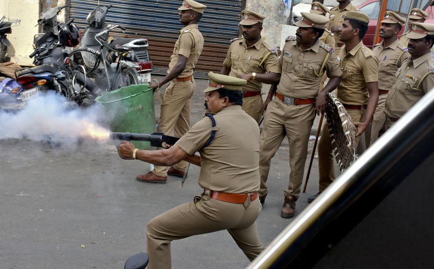A police officer fires tear gas to disperse protestors in Chennai, India, Monday, Jan.23, 2017. Fans of Jallikattu, a traditional bull-taming ritual attacked a police station with stones and set some vehicles on fire Monday in anger at being forcibly evicted from the beach where they been protesting for the past week in support of the sport. Jallikattu involves releasing a bull into a crowd of people who attempt to grab it and ride it. It is popular in Tamil Nadu state, but India&#39;s top court banned it in 2014 on grounds of animal cruelty. (AP Photo)