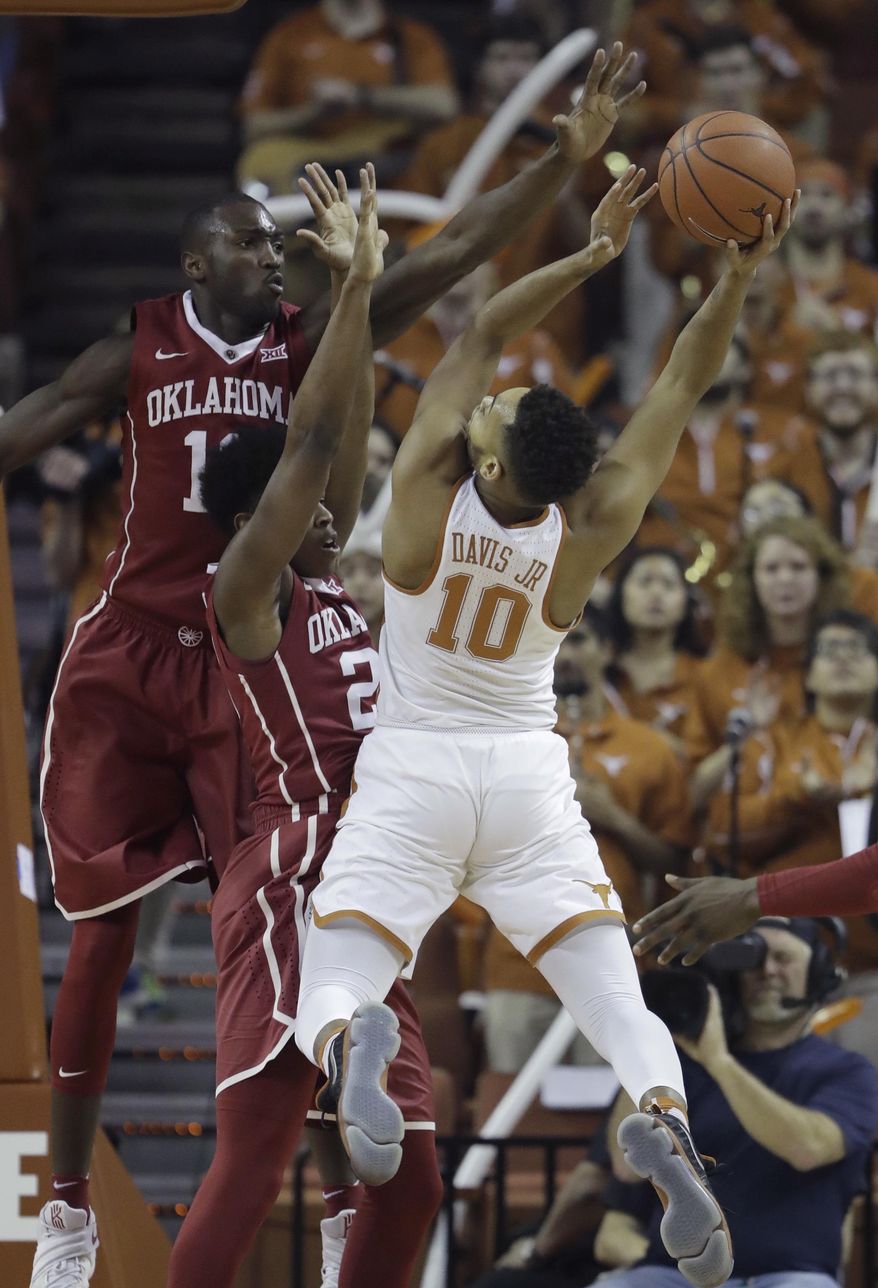 Texas guard Eric Davis Jr. (10) is defended by Oklahoma forward Khadeem Lattin (12) and Oklahoma guard Kameron McGusty, center, as he tries to shoot during the first half of an NCAA college basketball game, Monday, Jan. 23, 2017, in Austin, Texas. (AP Photo/Eric Gay)