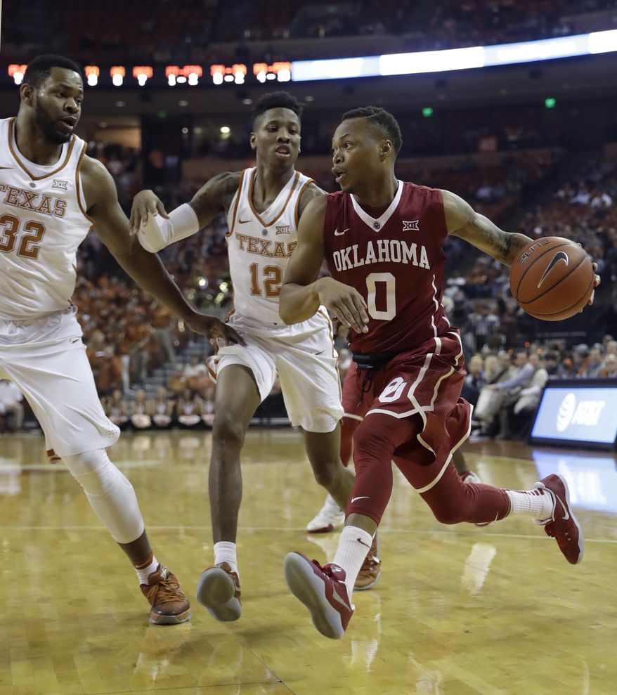 Oklahoma guard Darrion Strong-Moore (0) drives around Texas defenders Shaquille Cleare (32) and Kerwin Roach Jr. (12) during the first half of an NCAA college basketball game, Monday, Jan. 23, 2017, in Austin, Texas. (AP Photo/Eric Gay)