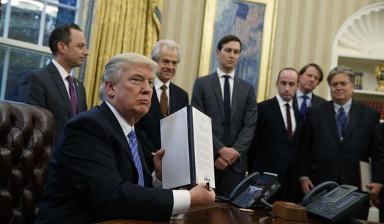 President Donald Trump shows off a signed executive order to reinstitute a policy barring any recipient of U.S. assistance from performing or promoting abortions abroad with money they receive from non-U.S. sources, Monday, Jan. 23, 2017, in the Oval Office of the White House in Washington. (AP Photo/Evan Vucci)