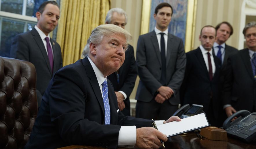 President Donald Trump looks up after signing the final of three executive orders, Monday, Jan. 23, 2017, in the Oval Office of the White House in Washington. (AP Photo/Evan Vucci)