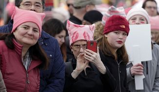 Women in pink caps look on as a women&#39;s march of tens of thousands begins to pass Saturday, Jan. 21, 2017, in Seattle. Women across the Pacific Northwest marched in solidarity with the Women&#39;s March on Washington and to send a message in support of women&#39;s rights and other causes. (AP Photo/Elaine Thompson)