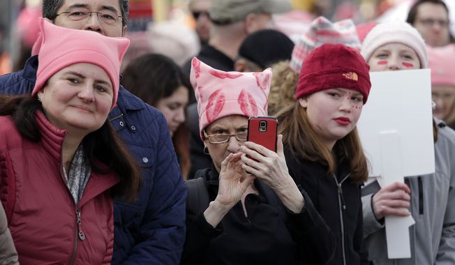 Women in pink caps look on as a women&#x27;s march of tens of thousands begins to pass Saturday, Jan. 21, 2017, in Seattle. Women across the Pacific Northwest marched in solidarity with the Women&#x27;s March on Washington and to send a message in support of women&#x27;s rights and other causes. (AP Photo/Elaine Thompson)