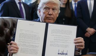 President Donald Trump shows off his signature on an executive order about the Dakota Access pipeline, Tuesday, Jan. 24, 2017, in the Oval Office of the White House in Washington. (AP Photo/Evan Vucci)