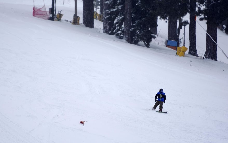 In this photo taken on Monday, Jan., 23, 2017, a snowboarder rides down a slope at Mountain High in Wrightwood, Calif., where several ski lifts were on hold due to ice and wind through out the day. Mountain High received between two to three feet of fresh snow and the "largest snow received in the last five years" according to a press release from the ski resort. (David Pardo/The Daily Press via AP)