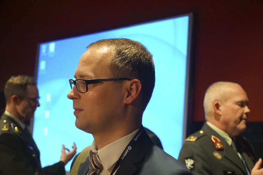 Estonian defense official Erki Kodar chats with a conference goer as part of a Cyber Security conference held in Lille, northern France, Tuesday, Jan. 24, 2017. Estonia is experimenting with the idea of cyberconscription, giving draftees with tech skills the chance to step into roles defending the military's electronic infrastructure. (AP Photo/Raphael Satter)