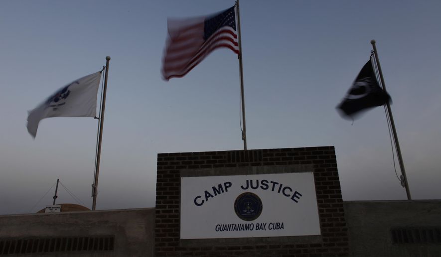 FILE - In this May 31, 2009 file photo reviewed by the U.S. military and made through a window, flags wave at the entrance to Camp Justice, the site of the U.S. war crimes tribunal compound on Guantanamo Bay U.S. Naval Base in Cuba. The first session of the Guantanamo Bay war crimes tribunal under President Donald Trump may have hit a snag. A pretrial hearing in the Sept. 11 terrorism case scheduled to start Tuesday, Jan. 24, 2017 and run through next week could be postponed because the lead attorney for one of the five defendants was unable to make it to the U.S. base in Cuba after breaking her arm in Washington over the weekend. (AP Photo/Brennan Linsley, Pool)