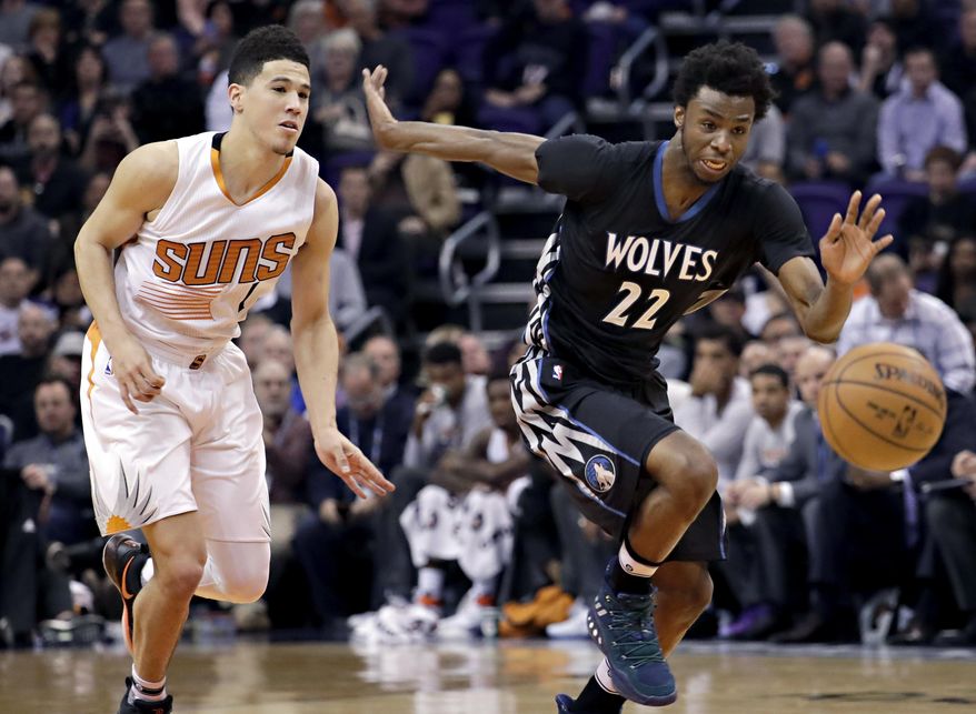 Minnesota Timberwolves forward Andrew Wiggins (22) and Phoenix Suns guard Devin Booker (1) chase down a loose ball during the first half of an NBA basketball game, Tuesday, Jan. 24, 2017, in Phoenix. (AP Photo/Matt York)