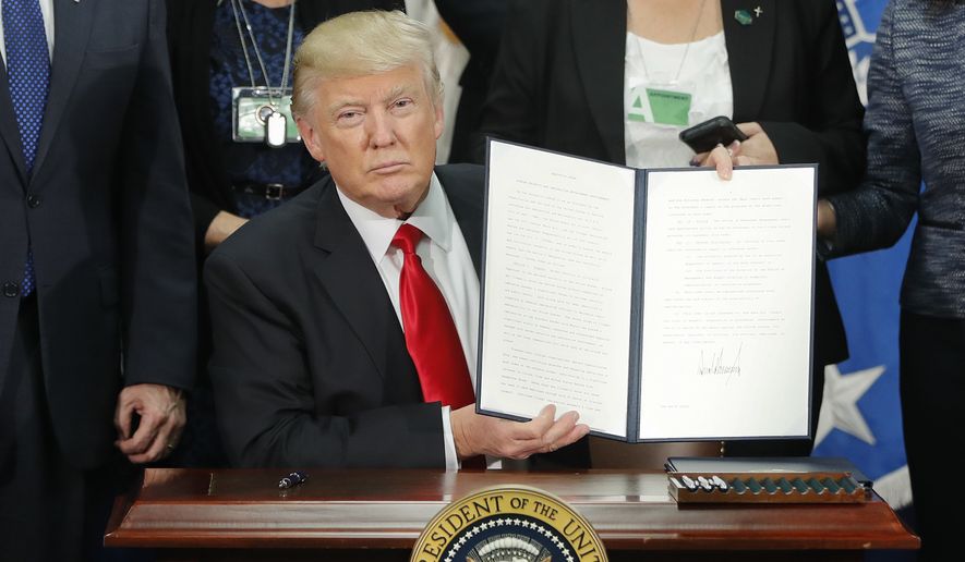 President Donald Trump holds up an executive order for border security and immigration enforcement improvements after signing the order during a visit to the Homeland Security Department headquarters in Washington, Wednesday, Jan. 25, 2017. (AP Photo/Pablo Martinez Monsivais)