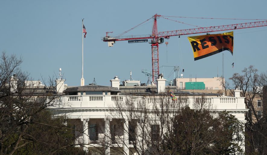 Greenpeace protesters unfurl a banner that reads "Resist" at the construction site of the former Washington Post building, near the White House in Washington, Wednesday, Jan. 25, 2017, after police say protesters climbed a crane at the site refusing to allow workers to work in the area. (AP Photo/Andrew Harnik)