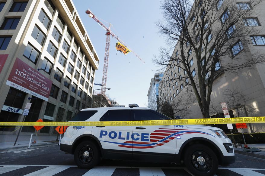 A police car blocks the street near the construction site of the former Washington Post building in Washington, Wednesday, Jan. 25, 2017, after Greenpeace protesters unfurled a banner that reads "Resist" at the site. (AP Photo/Alex Brandon)