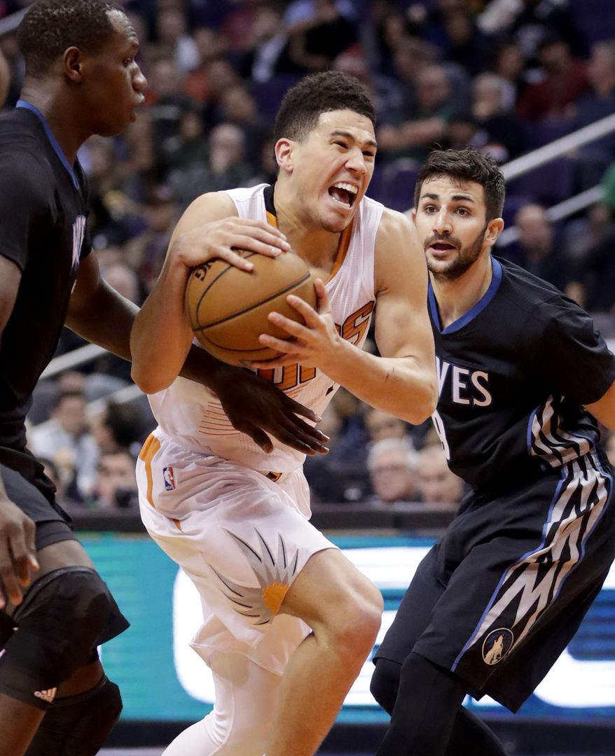 Phoenix Suns guard Devin Booker, center, drives past Minnesota Timberwolves guard Ricky Rubio, right, during the second half of an NBA basketball game, Tuesday, Jan. 24, 2017, in Phoenix. The Timberwolves won 112-111. (AP Photo/Matt York)
